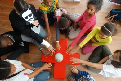 Un groupe d'enfants autour d'une croix-rouge en bois, symbole du Mouvement humanitaire